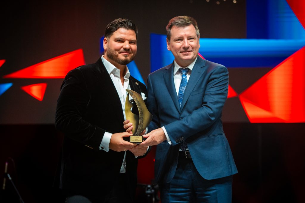 dwóch mężczyzn jeden z nich przekazuje statuetkę drugiemu