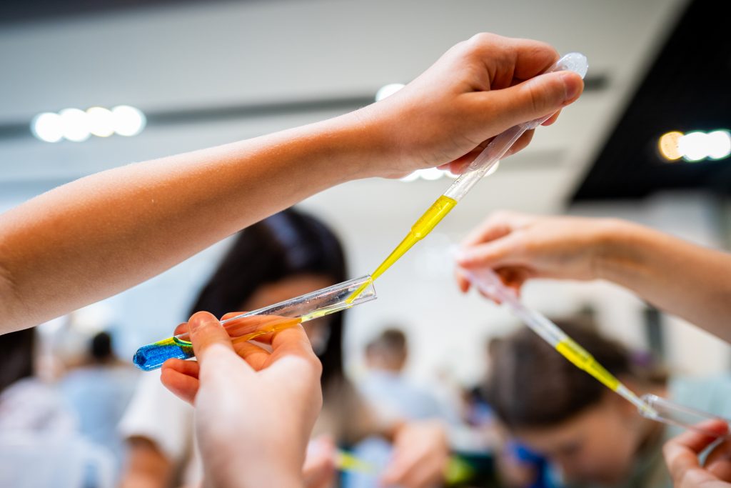 Dzieci wykonują eksperyment z wodą i kolorowymi cieczami podczas warsztatów edukacyjnych w Hydropolis